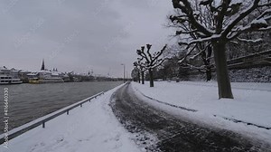 Flood on the River Main and the white, snow covered, empty river bank with a black walking path. Cold cloudy winter day in Würzburg. This beautiful historical german city is very rarely coverd in snow